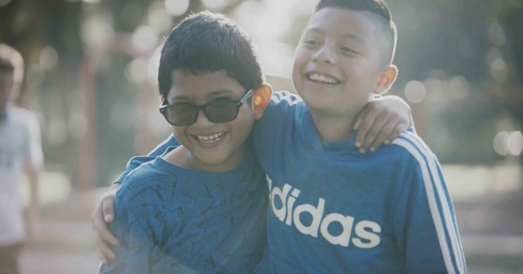 Two young boys embracing and smiling on a fundraising video for a children's charity.