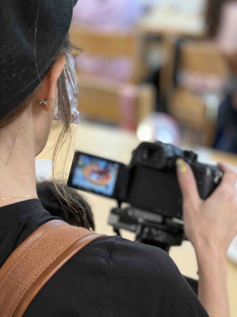 Over-the-shoulder shot of a video producer filming a fundraising video.