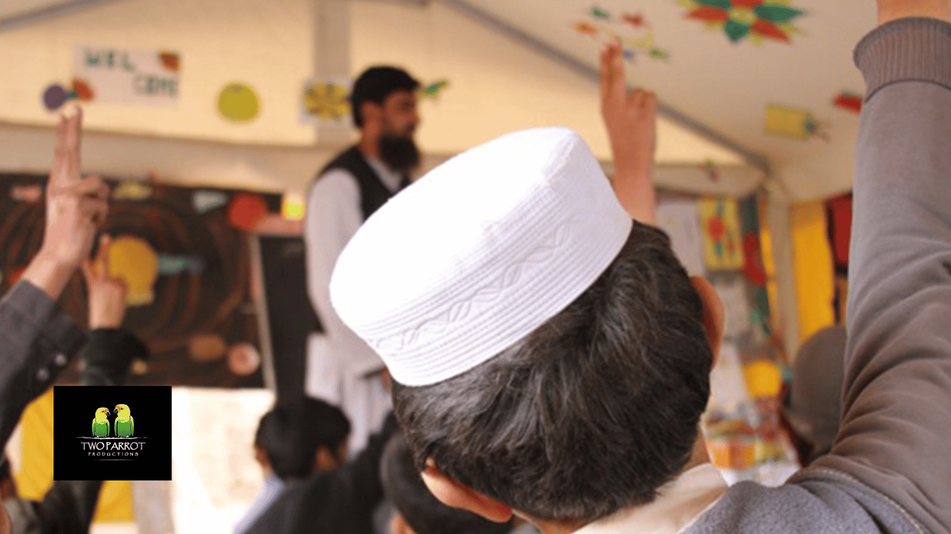 Young Muslim boy raising his hands in a classroom
